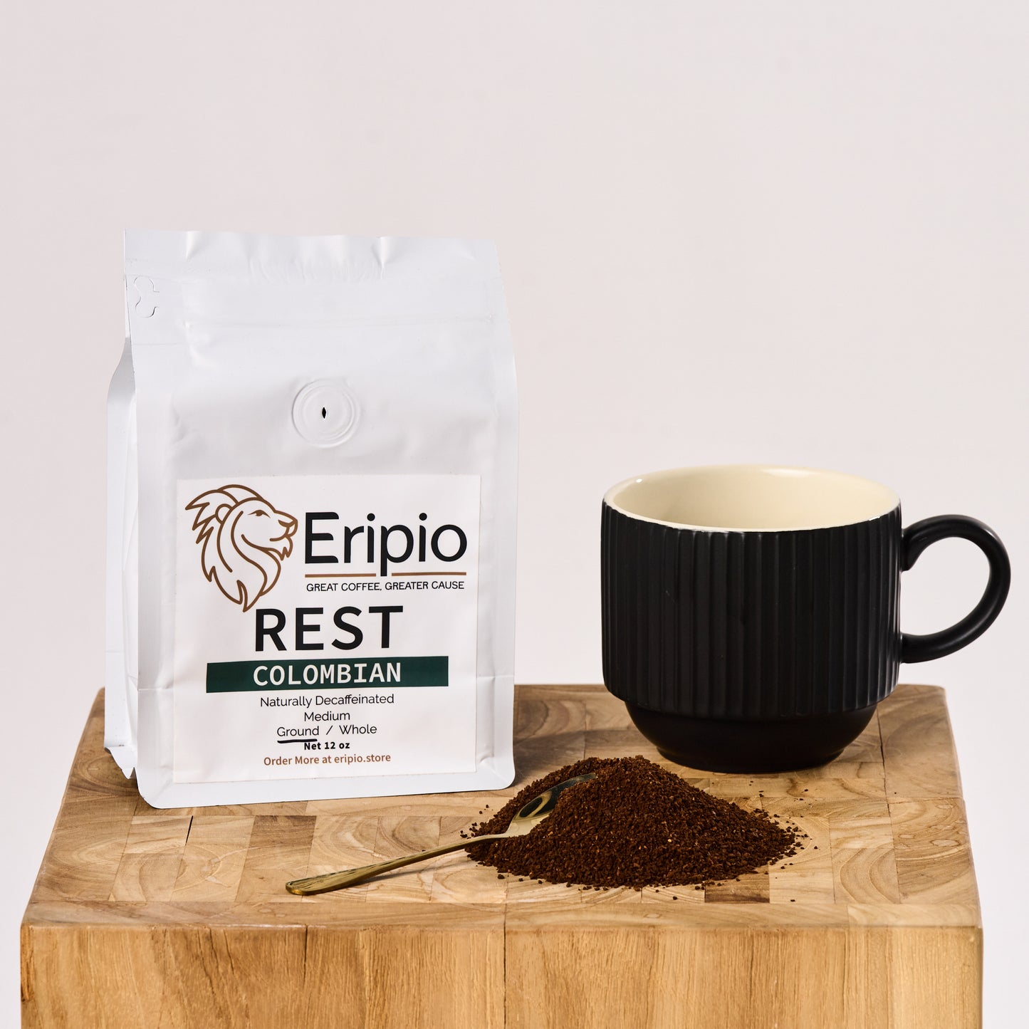 Eripio Rest Colombian decaf coffee package with a black mug and mound of ground coffee on a wooden surface.